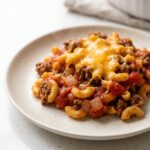 A serving of cheeseburger casserole with elbow macaroni, ground beef, and tomato under melted cheddar
