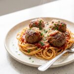 Homemade meatballs in marinara over spaghetti, topped with parmesan and fresh parsley